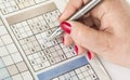 Woman`s hand with a pen is filling out sudoku Royalty Free Stock Photo