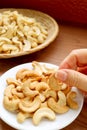 Woman`s Hand Picking a Roasted Cashew Nut Kernel from Snack Saucer