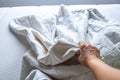 Woman right hand picking up white crumpled bed sheet on white bed, Close up shot, Selective focus, Bedroom cleaning concept Royalty Free Stock Photo