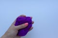 Woman`s hand with pink manicure holding a piece of violet wool on white background. Concept of felting creative hobby.