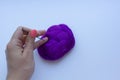 Woman`s hand with pink manicure sticking steel needle into the piece of violet wool on white background. Concept of felting creati