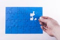 Woman's hand placing missing piece in Jigsaw puzzle signifying Royalty Free Stock Photo