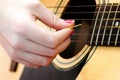 A woman's hand playing strings on a wooden guitar