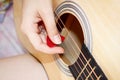 A woman`s hand plays a guitar pick on the strings Royalty Free Stock Photo