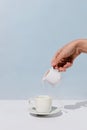 Woman`s hand pouring almond milk into cup of coffee on white Royalty Free Stock Photo