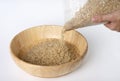 Woman`s hand is pouring raw brown rice packed in a plastic bag onto a wooden bowl Royalty Free Stock Photo