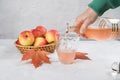 A woman's hand pours apple cider vinegar into a glass. Light background