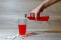 A woman's hand pours a red sports drink or lemonade into a glass Cup from a plastic bottle. Energy drink in glass and plastic bot