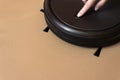 A woman`s hand presses a button Round Robot Vacuum Cleaner. Smart life technology concepts