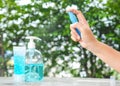 Womanâs hand pressing Alcohol Spray in the nature for clean her hand.