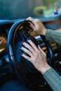 Woman's hand pressing the steering wheel of her car to honk the horn.