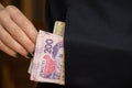 A woman's hand pulls out a pack of Ukrainian hryvnias from the pocket of a black jacket, money in the pocket Royalty Free Stock Photo