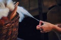A woman`s hand pulls yarn from a wicker basket. Spinner creates a thread of white wool Royalty Free Stock Photo