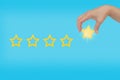 Woman's hand put the stars to complete five stars.copy space and blue background. giving a five Royalty Free Stock Photo