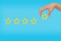 Woman's hand put the stars to complete five stars. copy space and blue background. giving a five Royalty Free Stock Photo