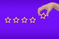 Woman\'s hand put the stars to complete five stars. copy space and purple background. giving a five star rating. Royalty Free Stock Photo