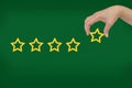 Woman's hand put the stars to complete five stars. Customer satisfaction concept. copy space and green background. Royalty Free Stock Photo