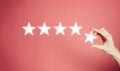 Woman`s hand put the stars to complete five stars. Customer satisfaction concept. copy space and pink background. giving a five Royalty Free Stock Photo