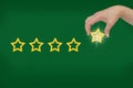 Woman's hand put the stars to complete five stars. Customer satisfaction concept. green background. giving a five Royalty Free Stock Photo