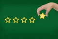 Woman's hand put the stars to complete five stars. Customer satisfaction concept green background. giving a five Royalty Free Stock Photo