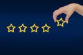 Woman's hand put the stars to complete five stars. copy space and blue background. giving a five Royalty Free Stock Photo