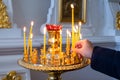 A woman`s hand puts a candle in front of an icon in an Orthodox church. Royalty Free Stock Photo