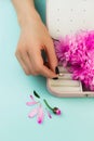 Woman`s hand puts diamond ring in the jewellery box. Beautiful accessory on blue with pink flowers Royalty Free Stock Photo