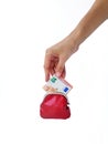 A woman`s hand puts money in a red purse with a metal lock on a white background. Saving money. Royalty Free Stock Photo