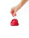 A woman`s hand puts money in a red purse with a metal lock on a white background. Saving money. Royalty Free Stock Photo