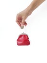 A woman`s hand puts money in a red purse with a metal lock on a white background. Saving money. Royalty Free Stock Photo