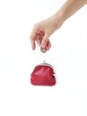 A woman`s hand puts money in a red purse with a metal lock on a white background. Saving money. Royalty Free Stock Photo