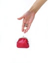 A woman`s hand puts money in a red purse with a metal lock on a white background. Saving money. Royalty Free Stock Photo