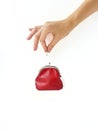 A woman`s hand puts money in a red purse with a metal lock on a white background. Saving money. Royalty Free Stock Photo