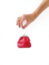 A woman`s hand puts money in a red purse with a metal lock on a white background. Saving money. Royalty Free Stock Photo