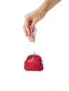 A woman`s hand puts money in a red purse with a metal lock on a white background. Saving money. Royalty Free Stock Photo