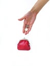 A woman`s hand puts money in a red purse with a metal lock on a white background. Saving money. Royalty Free Stock Photo