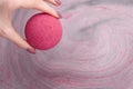 Woman`s hand putting bath bomb into water Royalty Free Stock Photo