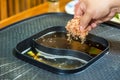 A woman`s hand is putting dried oysters in broth in an electric stove to make Japanese broth