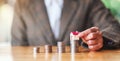 A woman`s hand putting house model on top of coins stack for saving money concept Royalty Free Stock Photo