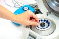 Woman's hand putting small tube into medical centrifuge