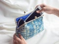 Woman`s hand putting white smartphone and sunglasses in vintage indigo blue fabric purse Royalty Free Stock Photo