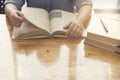 woman's hand reading book on wooden table