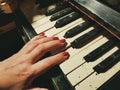 A woman`s hand with a red manicure on the keys of an old destroyed piano