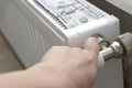 Woman's hand reduces the temperature in the radiator. Saving gas. Energy crisis concept.