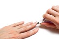 Woman`s hand removing nail cuticle on light white table. Care about dry, overgrown cuticle. Closeup.