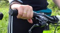 Woman`s hand with ring on the handlebars of a mountain bike in the park close-up. The biker leans on the handlebars of the bike