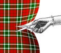 Woman`s hand with scissors cutting tartan fabric