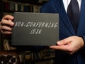 Woman`s hand showing black notepad with phrase NON-CONFORMING LOAN - closeup shot on grey background