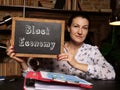 Woman`s hand showing chalkboard with phrase Black Economy - closeup shot on grey background