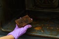 A woman`s hand shows a very dirty sponge after cleaning the oven. Detergent efficiency concept.